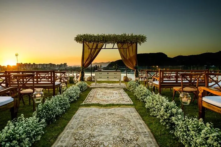 Pergolado com cortinas ao pôr do sol e nave de flores brancas