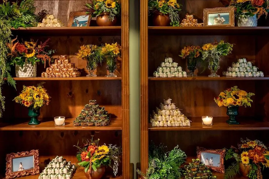 Estante de madeira com doces, flores amarelas e porta-retratos